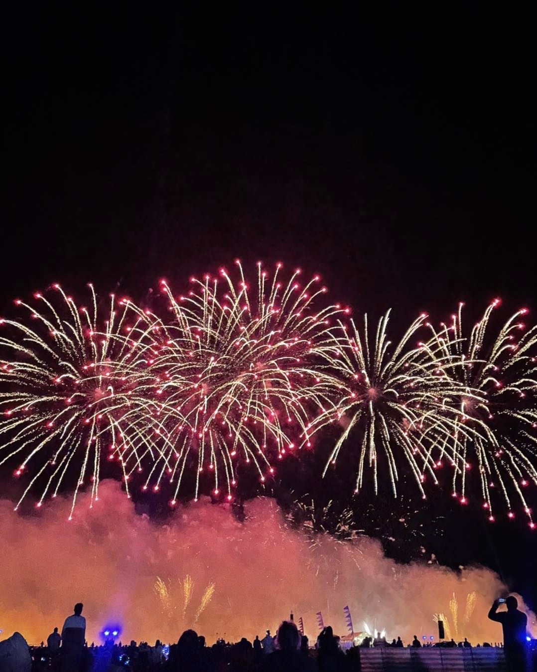 Explosive fireworks burst reflected above the crowd